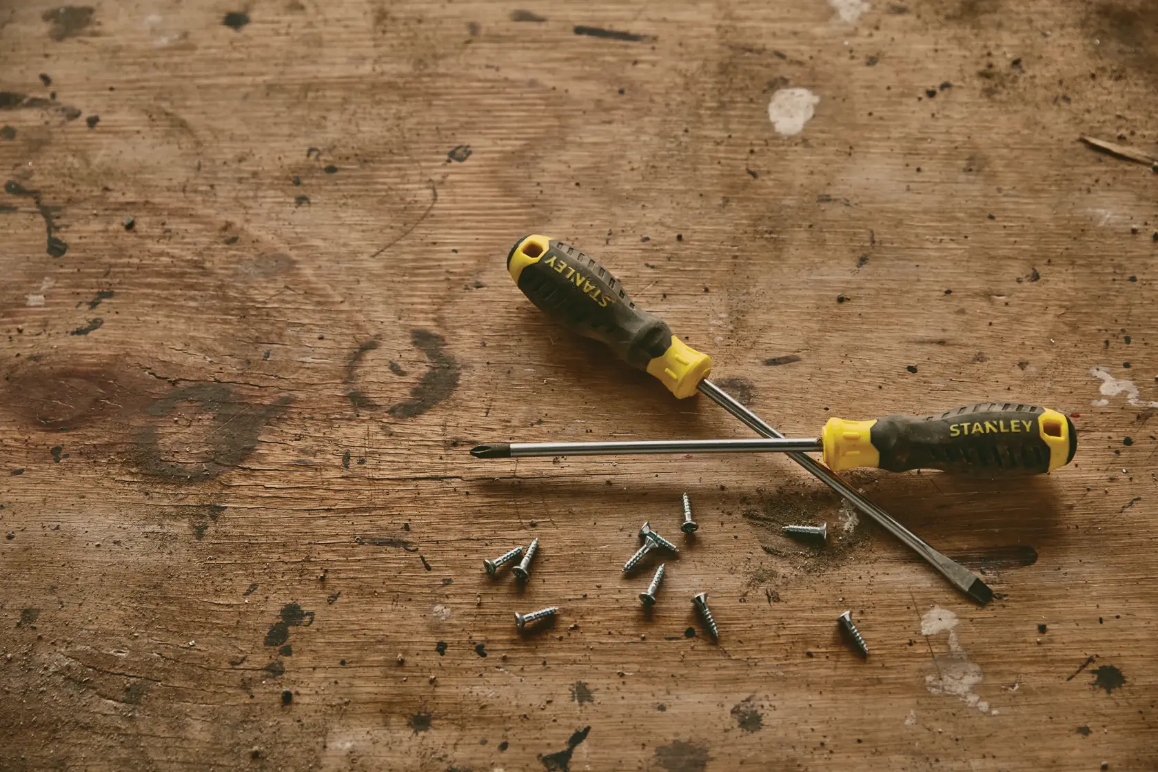 Photo of STANLEY STMT60811-840_STMT60828-840 screwdrivers and screws on a worn wooden surface.