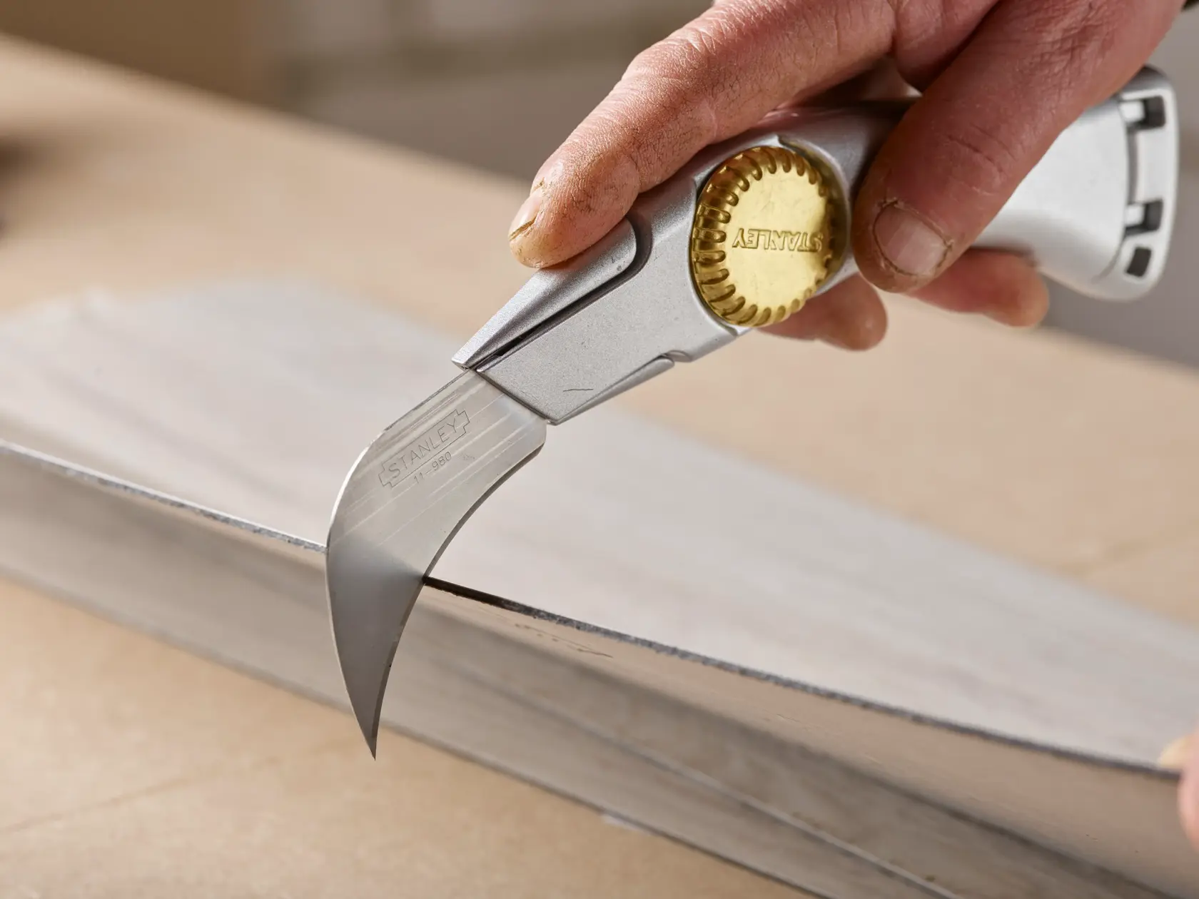 STANLEY 0-11-980 hooked blade utility knife cutting metal sheet, close-up photography.