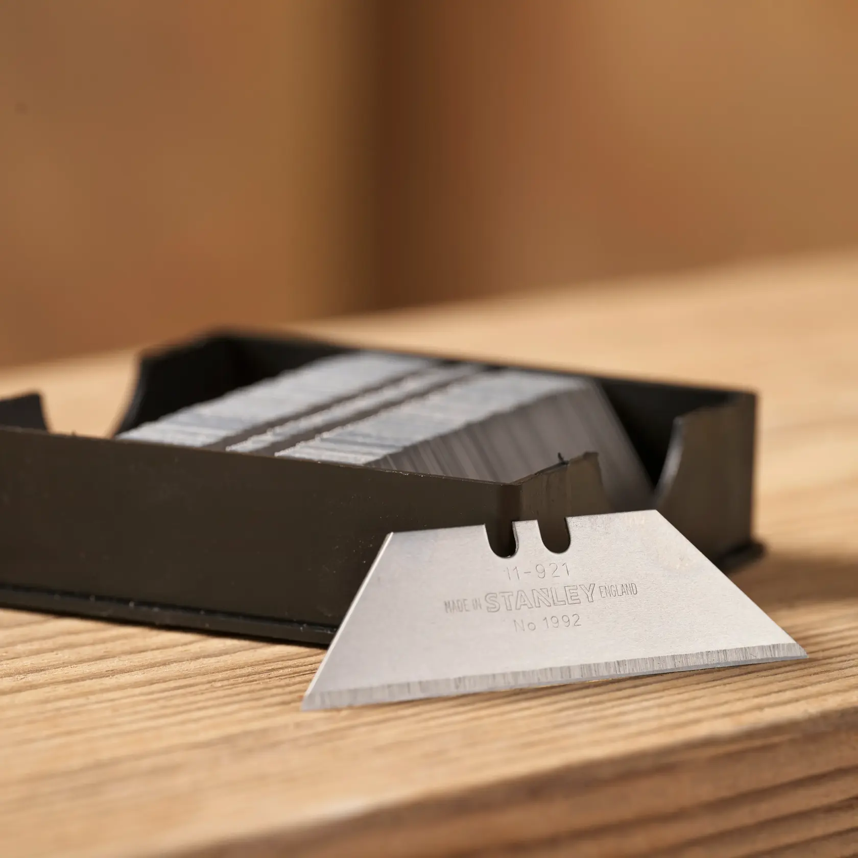 Stanley 1-11-921 utility blades in black dispenser, close-up on wooden surface.