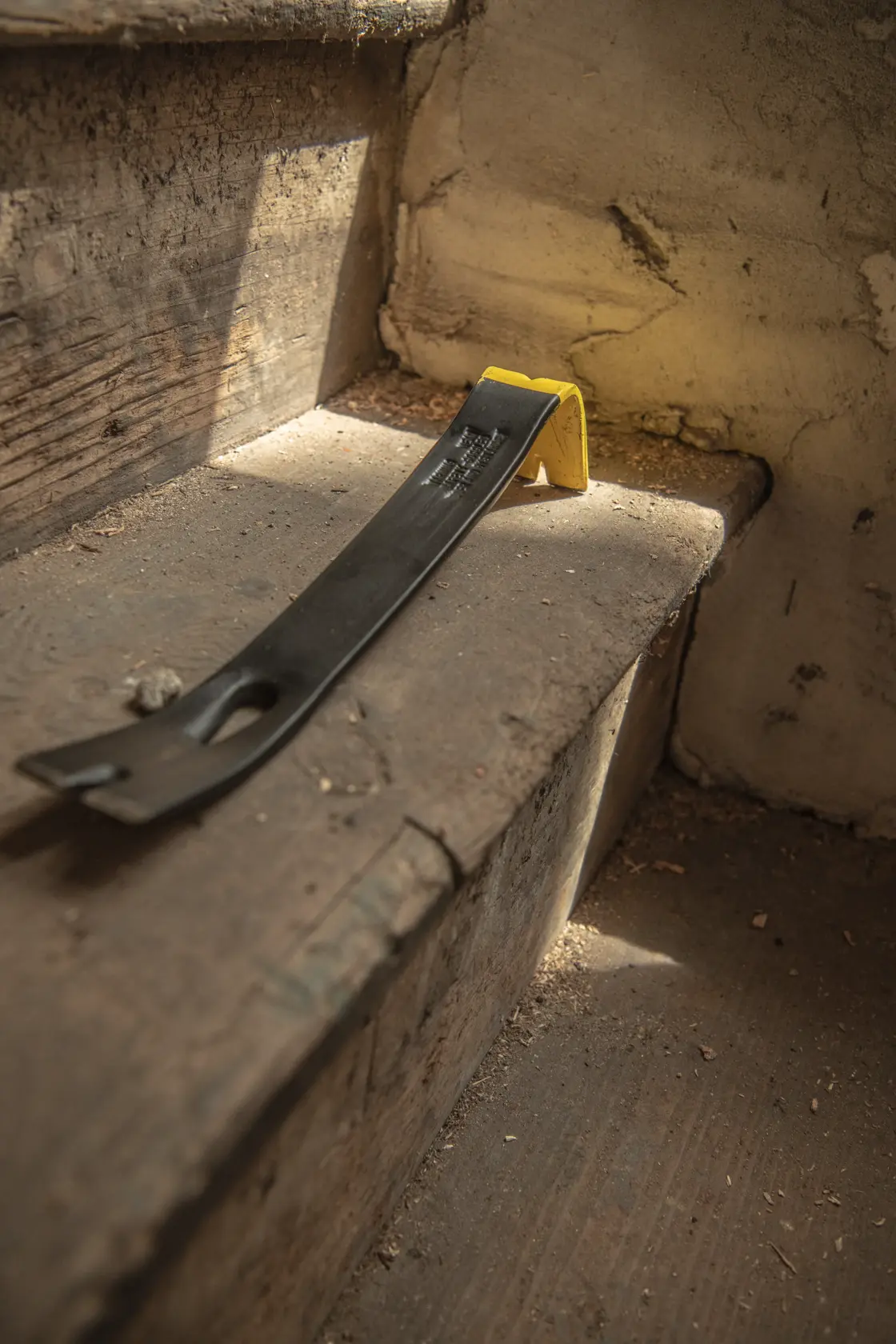 STANLEY 55-515 pry bar with yellow end cap on worn wooden stairs, angled view, natural lighting.