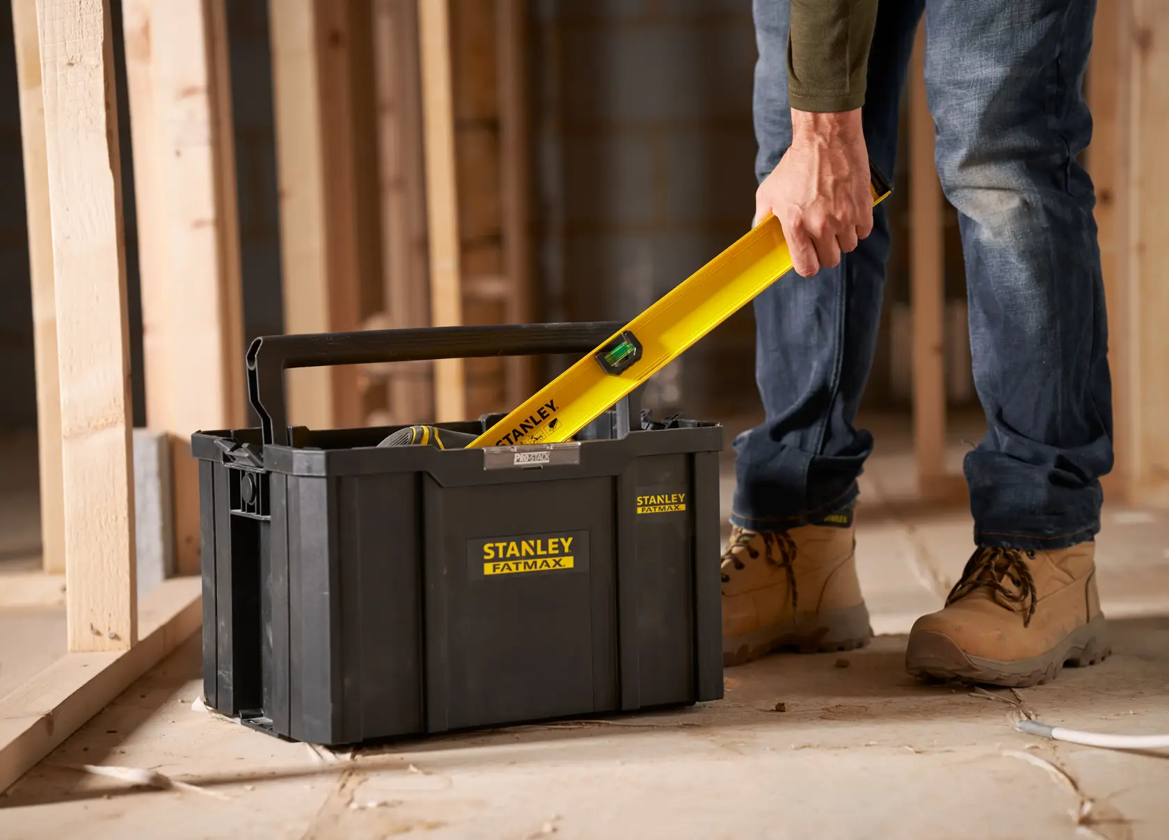 Stanley FMST1-75794 toolbox with handle, shown on construction site, person placing yellow level inside