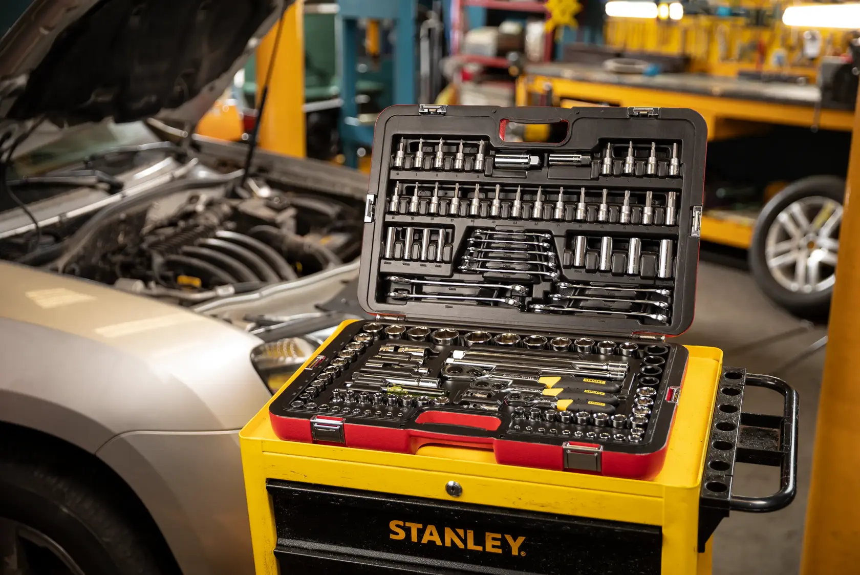 STANLEY R99-120LA mechanic tool set open on yellow tool chest, automotive workshop background.