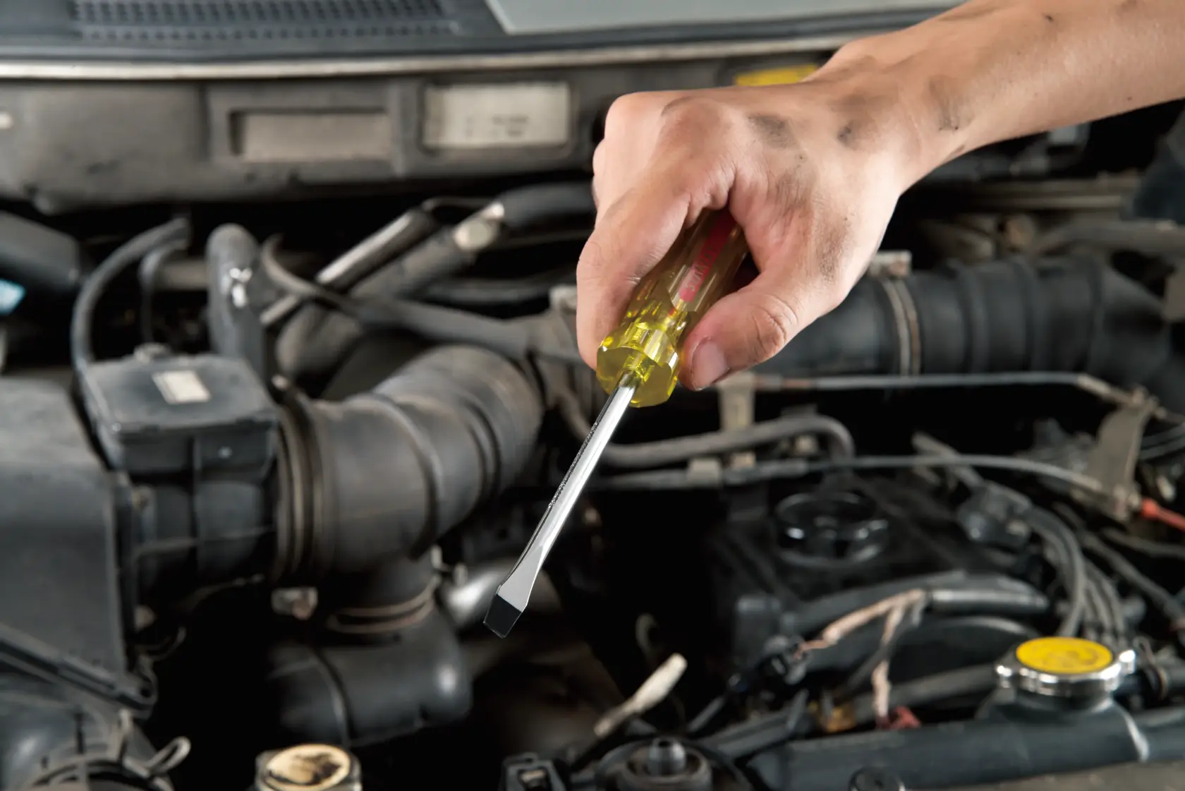 STANLEY 62-247 flathead screwdriver with yellow handle in use working on a car engine, close-up view.