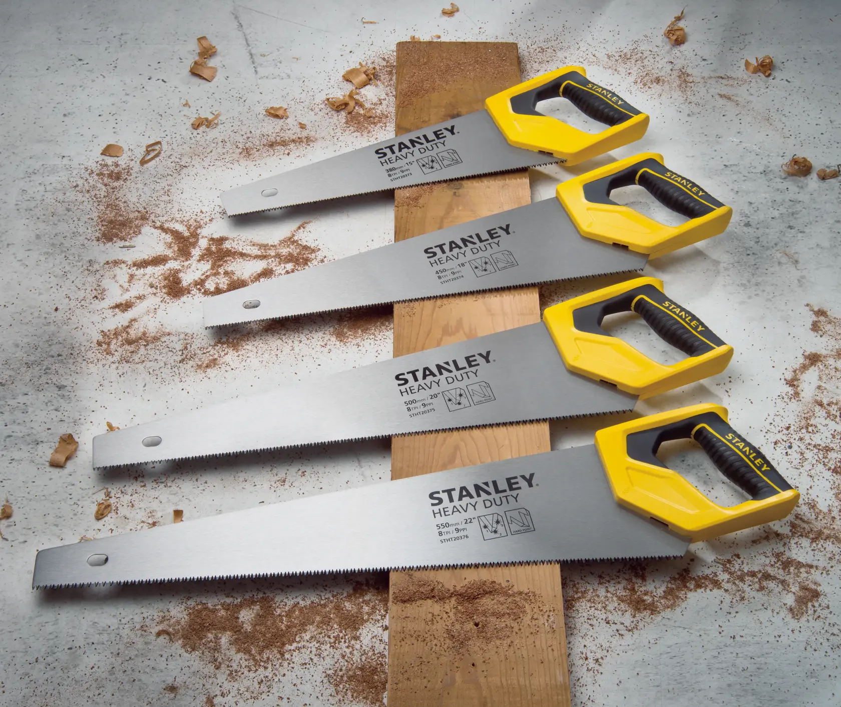 STANLEY STHT20375-LA heavy duty hand saws with yellow handles on wood, angled view, surrounded by sawdust.
