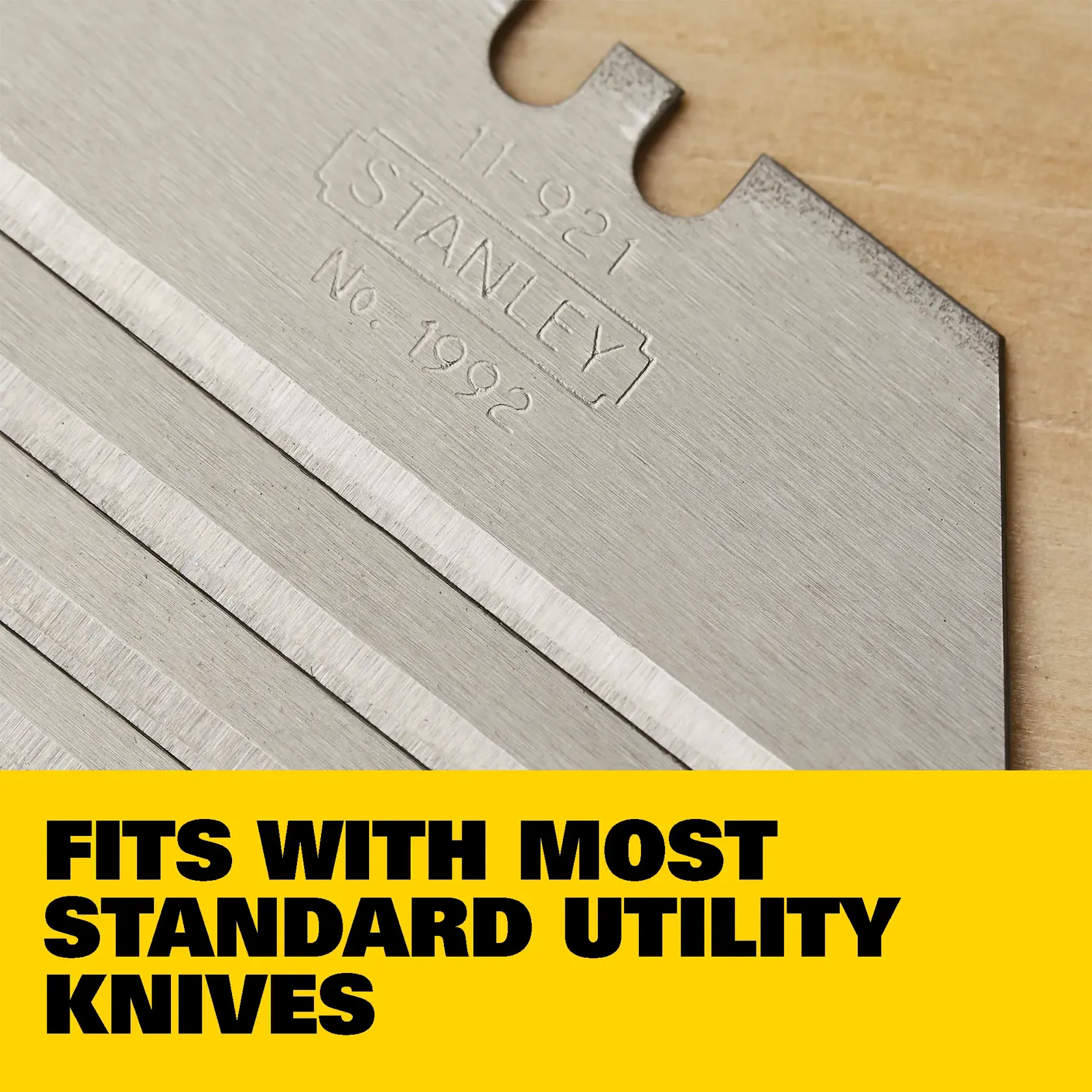 A Stanley utility knife blade with a precision-honed edge is shown lying on a wooden surface. The image highlights the blade's accuracy and sharpness for consistent cuts.