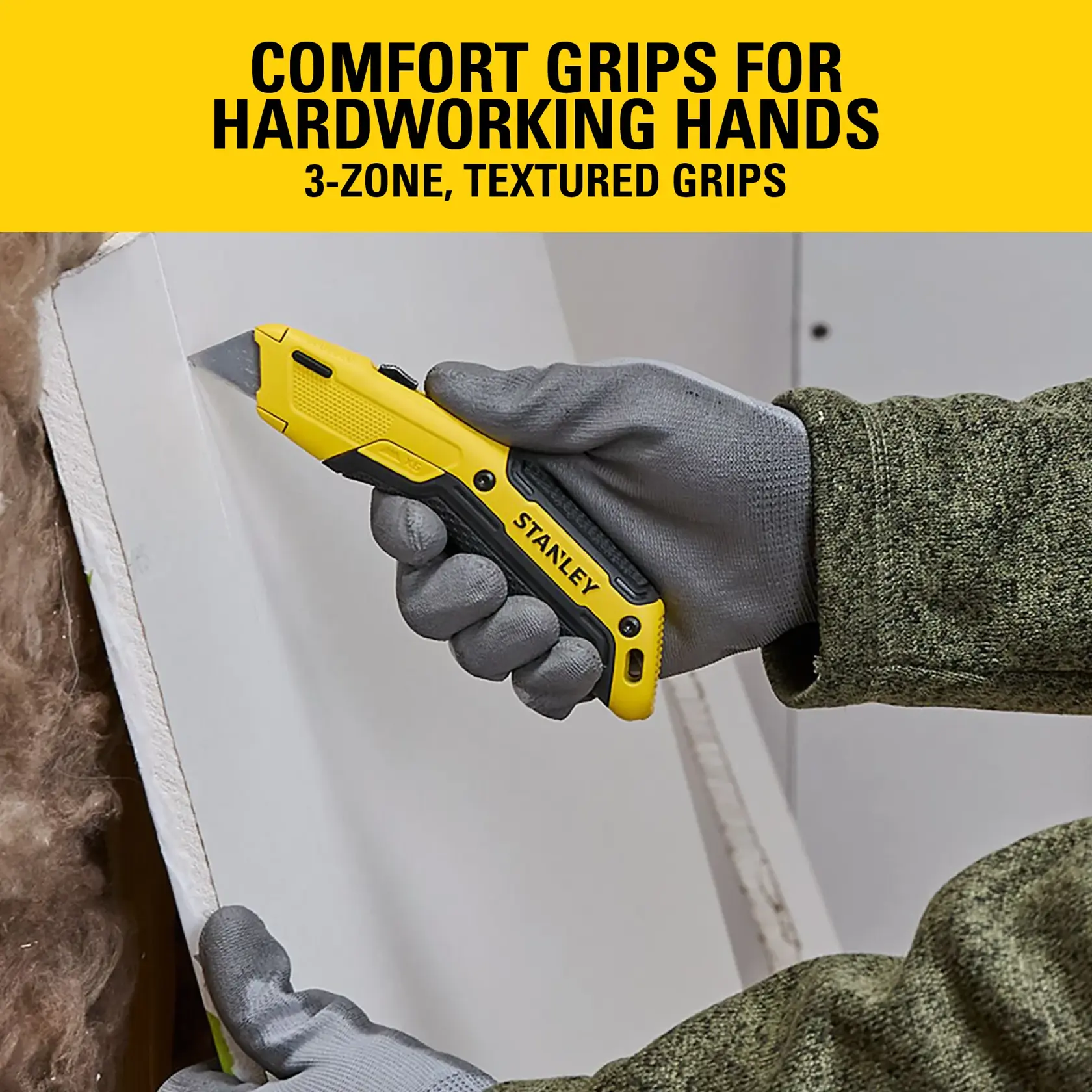 Stanley utility knife with comfort grips used to cut drywall by a gloved hand, yellow and black handle shown.