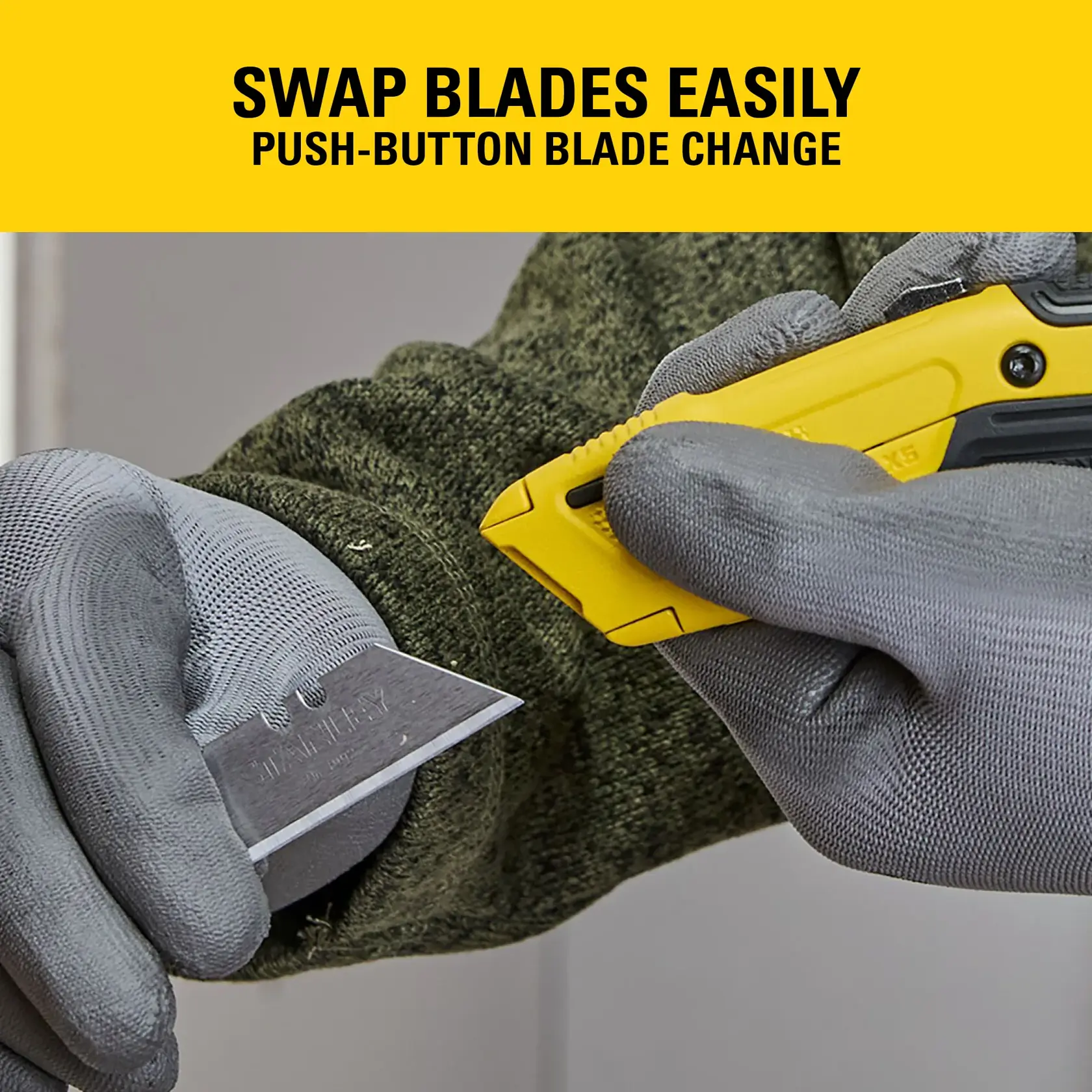 Gloved hands swap blades on a yellow Stanley utility knife with push-button blade change feature.