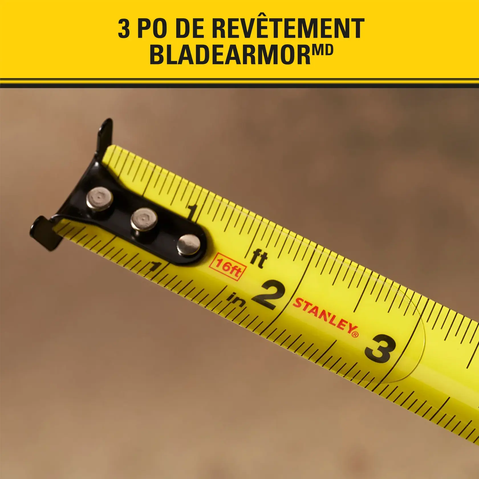 Gros plan sur un mètre ruban STANLEY montrant les premières mesures en pouces et pieds. Le ruban est jaune avec des chiffres et du texte noirs. En haut de l’image, un texte en français annonce '3 po de revêtement BLADEARMOR.'