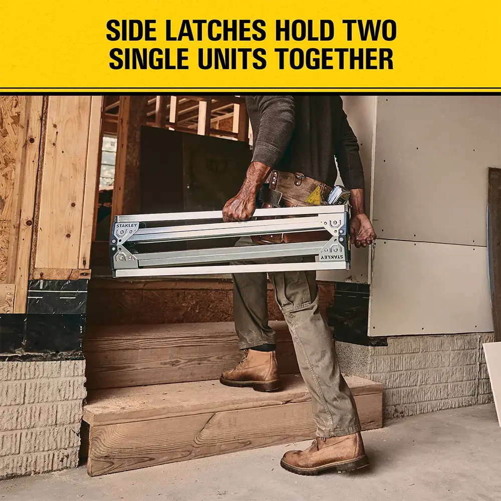 A person carries two STANLEY storage units fastened together with side latches. The image also has text stating, 'SIDE LATCHES HOLD TWO SINGLE UNITS TOGETHER.'