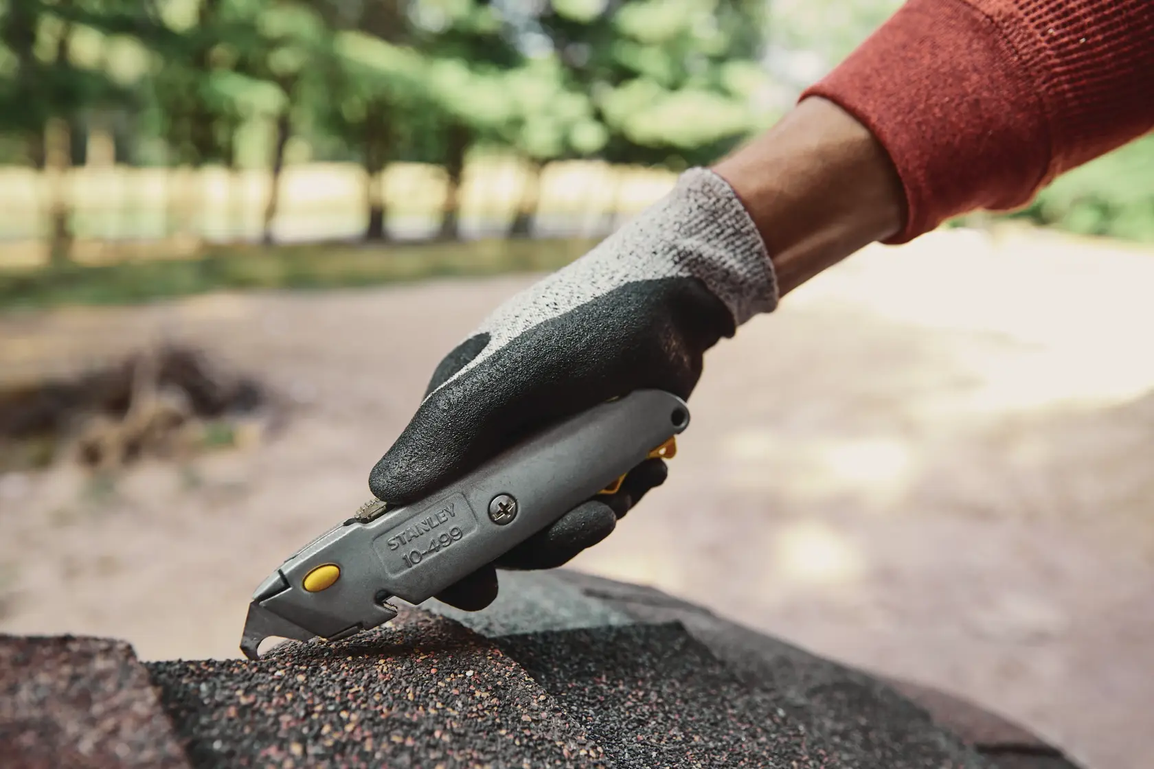 Stanley 10-499 couteau utilitaire utilisé sur matériau de toiture en extérieur, vue latérale rapprochée.