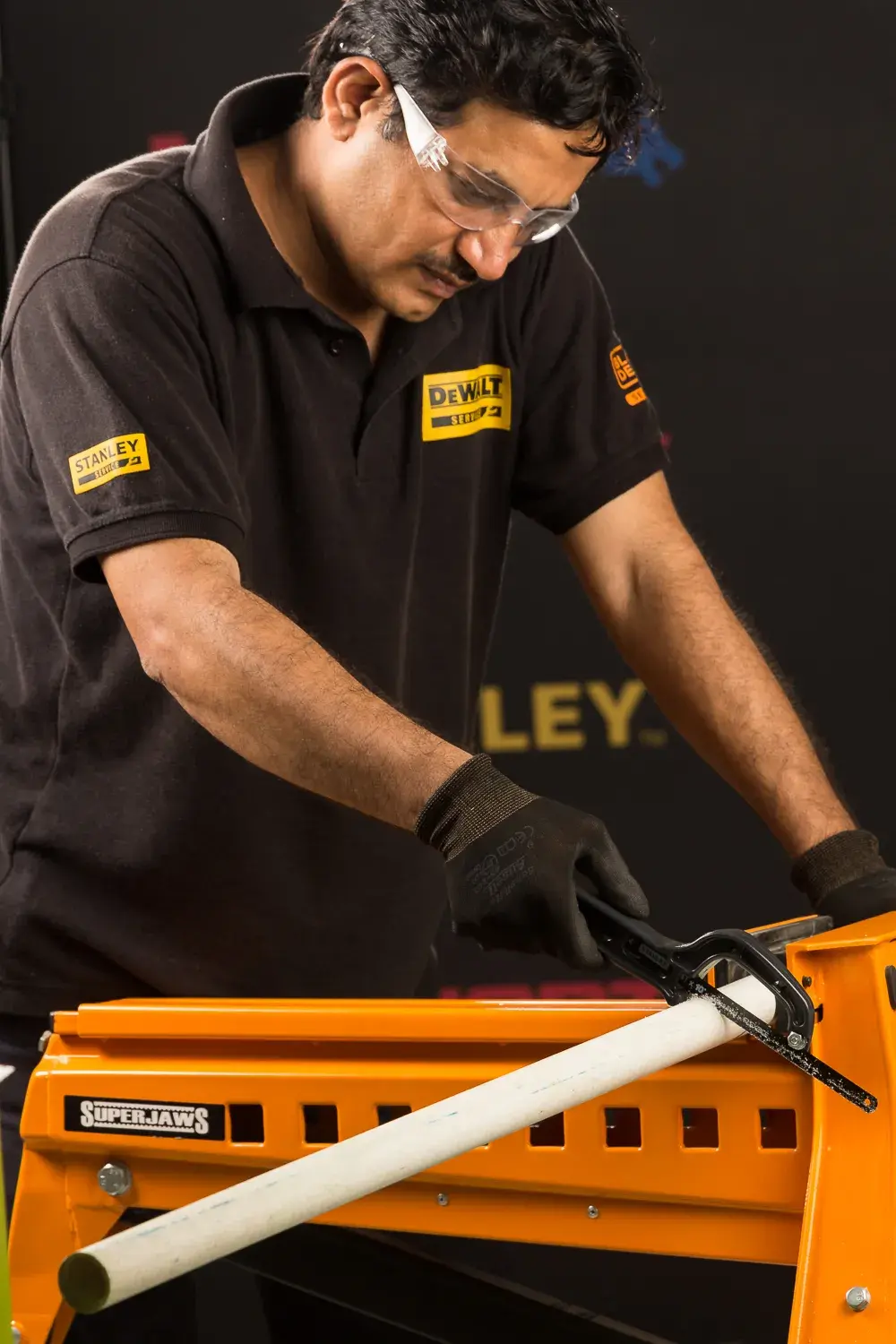 STANLEY 20-807 handsaw cutting pipe on orange workbench, close-up angle.