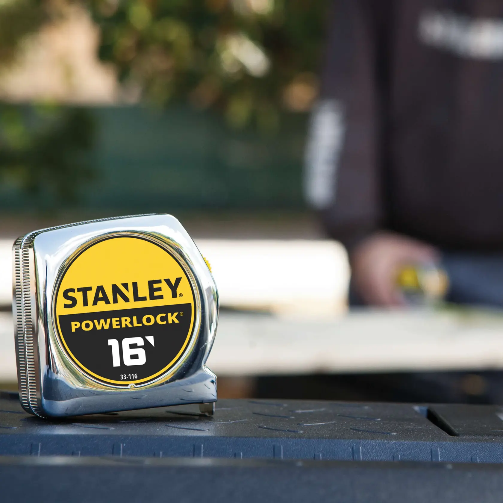 STANLEY 33-116 tape measure with chrome case and yellow-black label, photography with outdoor background.