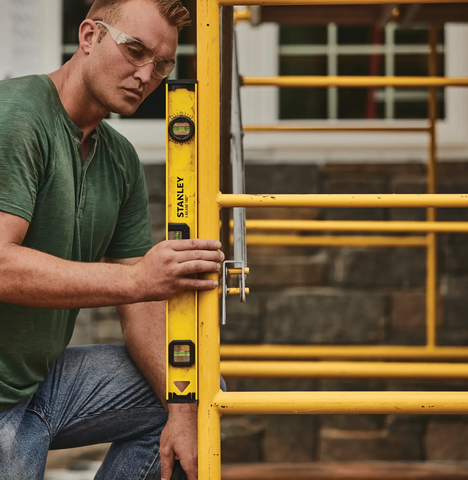 Niveau Stanley 42-324 tenu contre un échafaudage jaune en extérieur, photographie de produit.