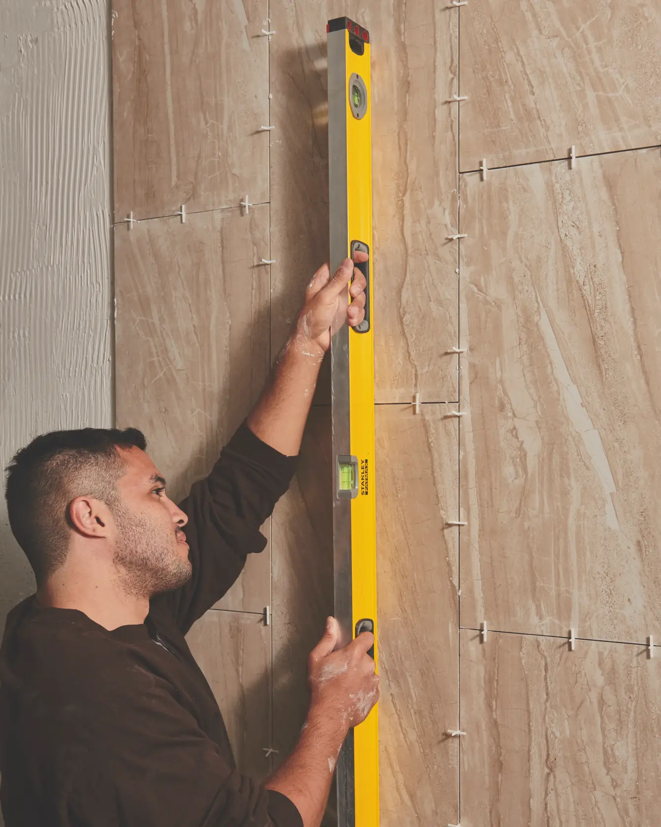 STANLEY 43-548 level tool held vertically against wall tiles in use, front angled photography.