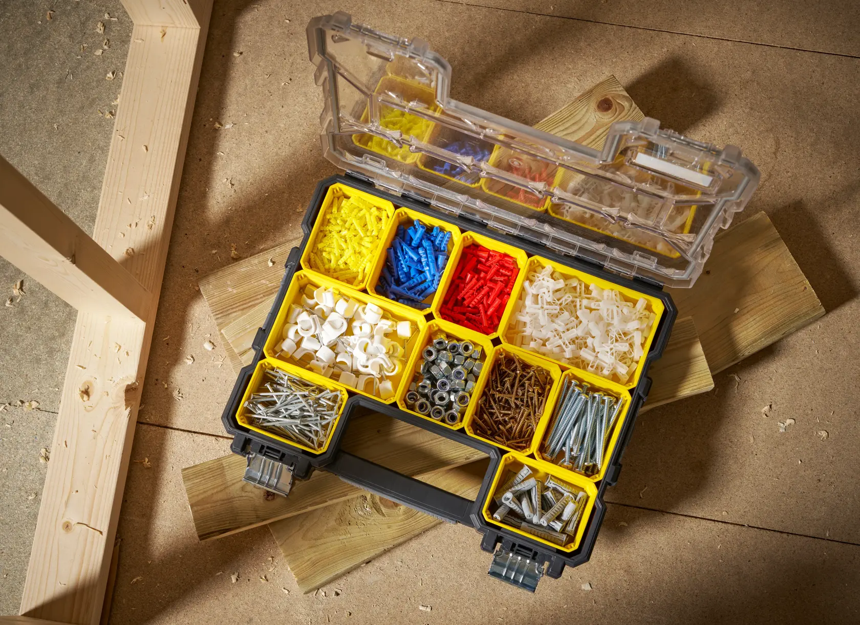 STANLEY FMST14820 organizer box with yellow compartments filled with assorted hardware, open on a workshop floor.