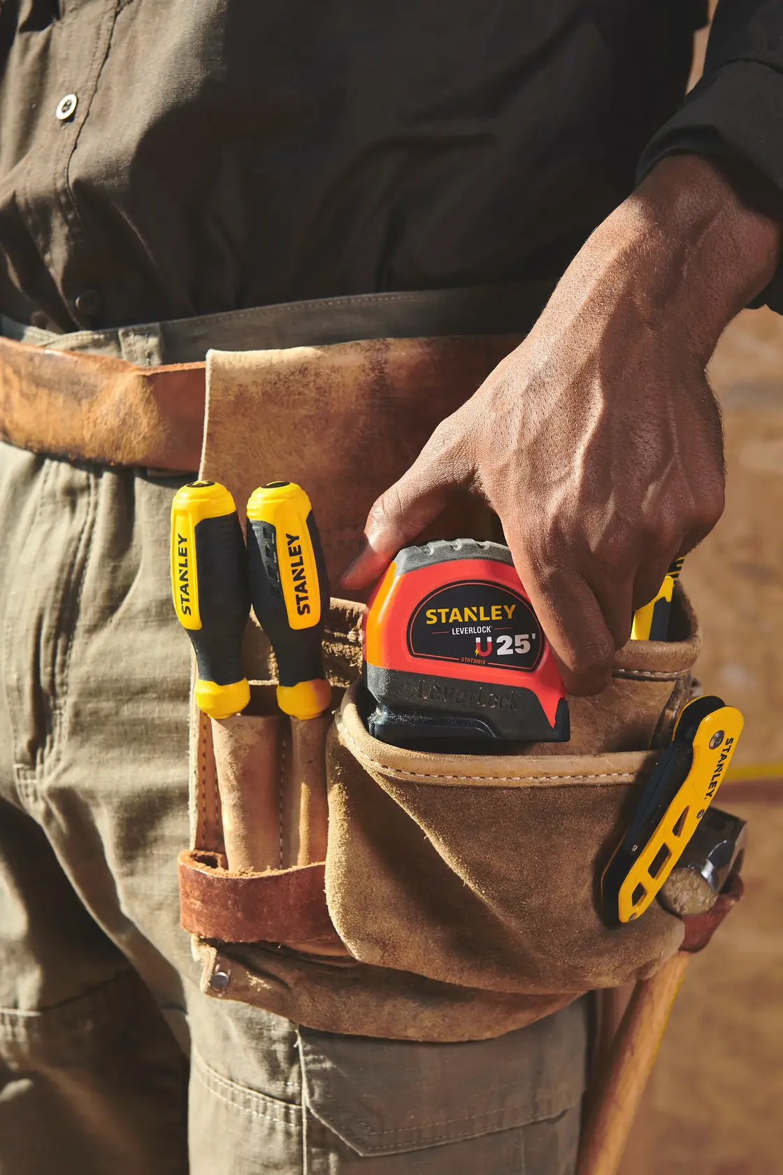 Photo of STANLEY STHT30818S measuring tape and tools in a leather tool belt, close-up view.