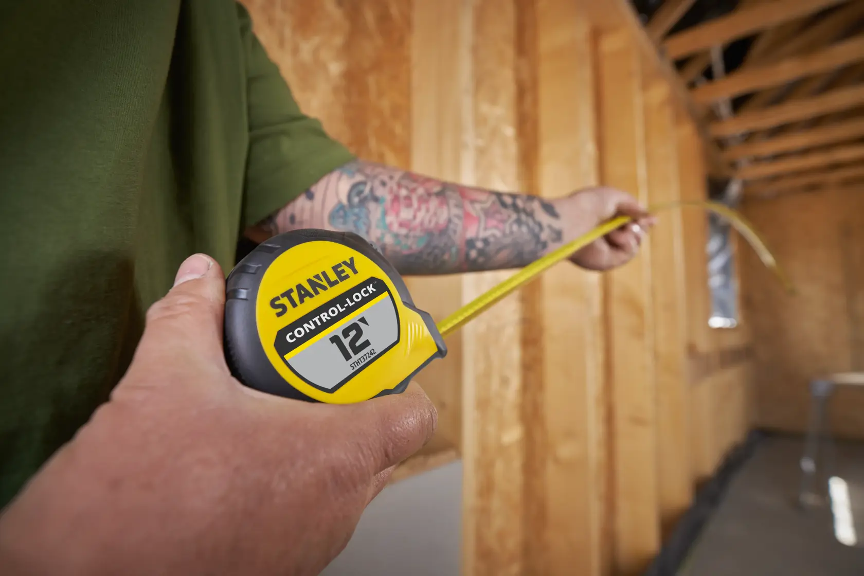 Photo of STANLEY STHT37242 tape measure in use, yellow and black, measuring inside a wooden framed room.