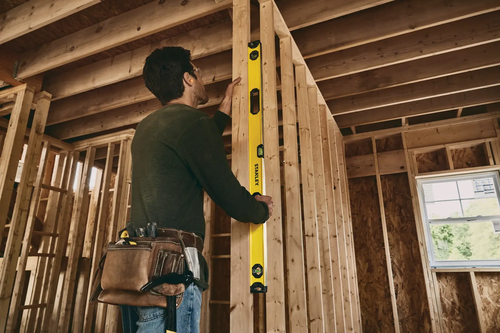 Stanley STHT42504 level tool used on wooden framing during construction, tool belt visible.