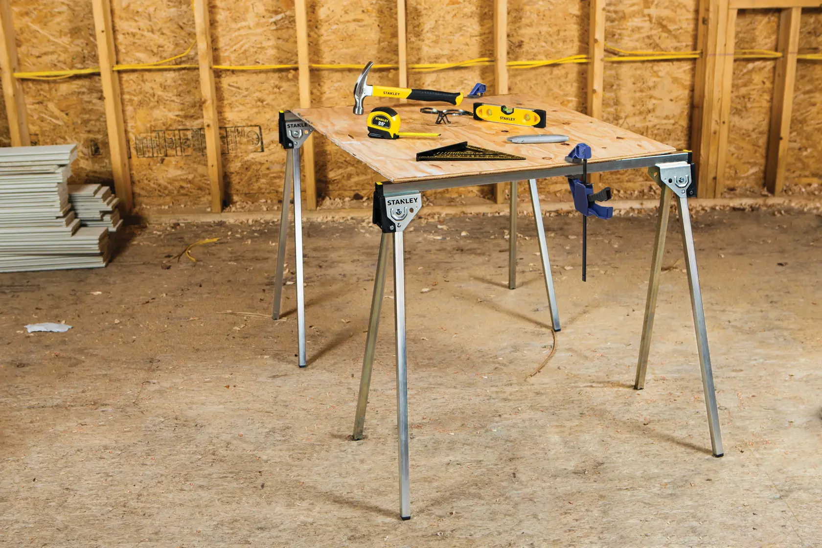 STANLEY STST11154 folding metal sawhorse set up as a work table with tools on top, shown in workshop environment.