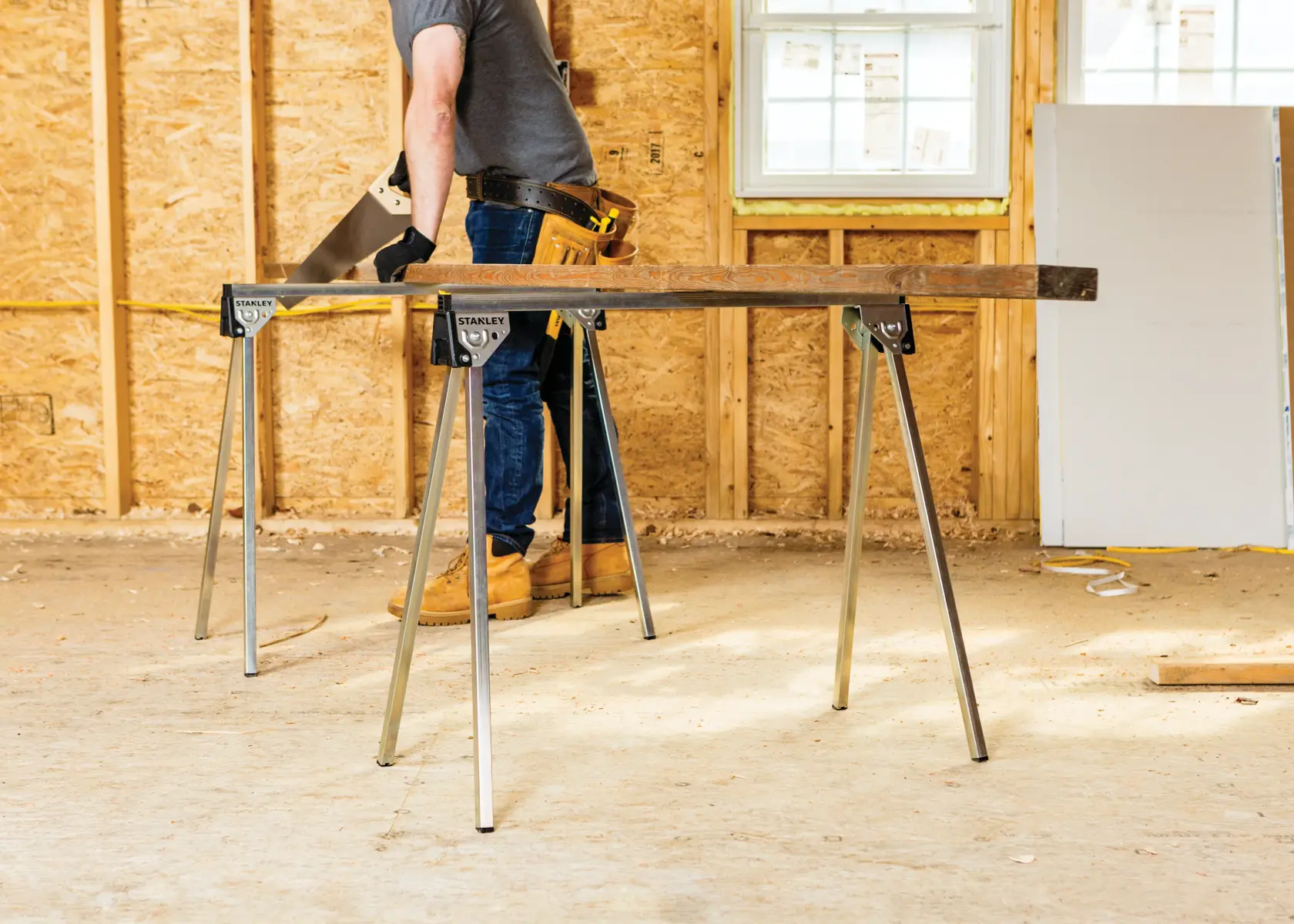 STANLEY STST11154 sawhorses supporting a wooden board in a construction setting, shown from the side.