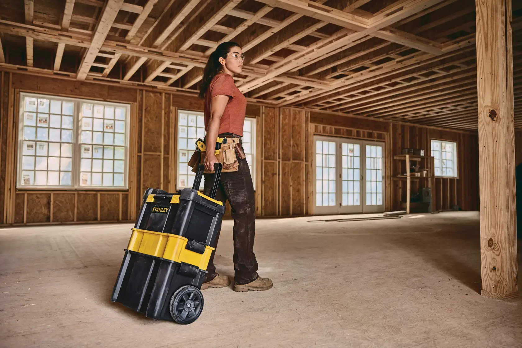 STANLEY STST18631 rolling tool box with yellow and black design in a construction site, pulled by a worker.