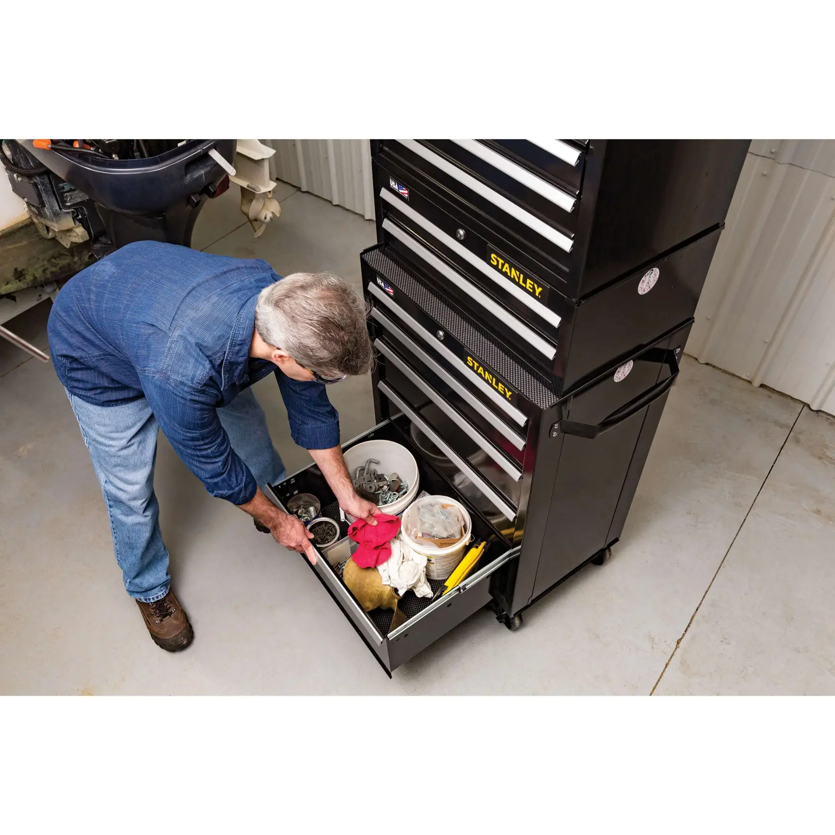 Stanley STST22753BK tool chest with open drawer, man organizing tools and accessories in a garage setting.