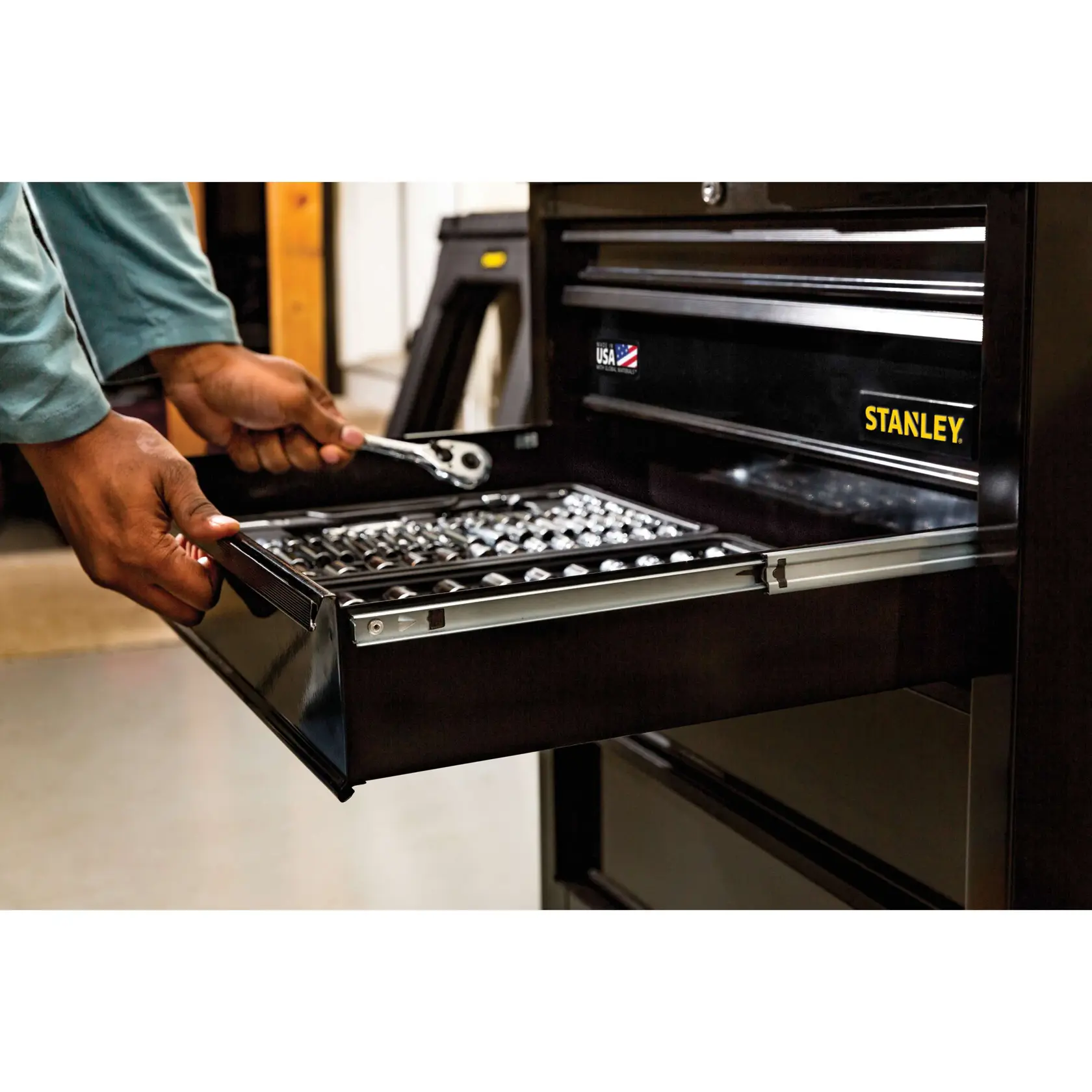 STANLEY STST23151BK tool chest drawer open, hand holding ratchet, showing organized sockets, front angle.